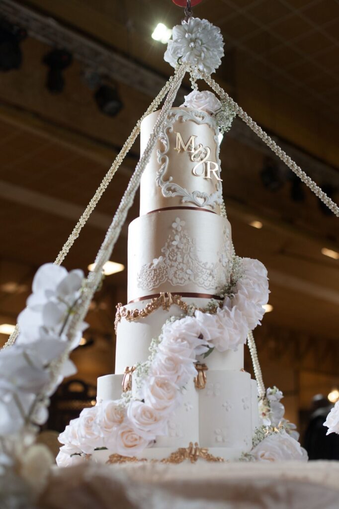 Suspended ivory and gold wedding cake with monogram plaque